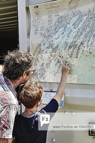 Vater und Sohn untersuchen eine an der Wand hängende Karte  Portland  Maine  USA