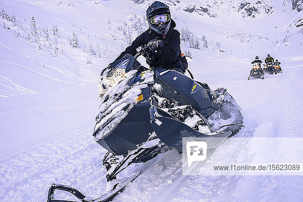 Adventurous man looking at camera while riding snowmobile in Callaghan Valley  Whistler  British Columbia  Canada