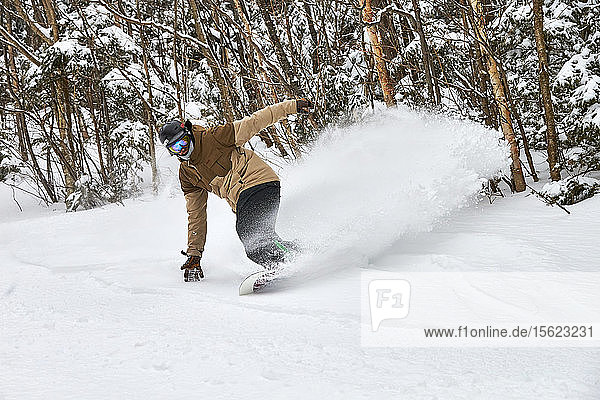 A snowboarder slashing powder inbounds at Sugarbush  VT.