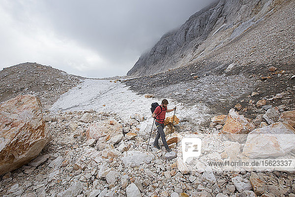 Ein Wanderer  der an einem kleinen Gletscherfeld in der mondähnlichen Landschaft des Gipfelplateaus auf dem Triglav  dem höchsten Berg Sloweniens  vorbeigeht