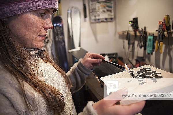 Seitenansicht einer Frau mit Strickmütze beim Wachsen von Skiern in einer Garage  Missoula  Montana  USA