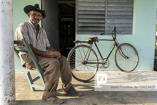 Mann sitzt auf einem Stuhl und posiert für ein Porträt vor seinem Haus  Vinales  Provinz Pinar del Rio  Kuba
