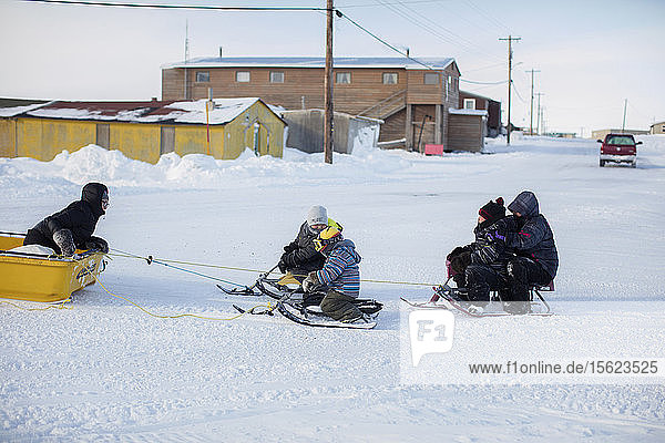 Children are pulled by a snowmobile through the streets of Tuktoyaktuk  Northwest Territories  Canada  March 13  2016.