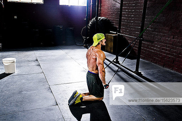A crossfit athlete works out with resistance bands in an old gritty gym in San Diego  CA.