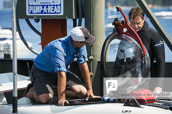 Two men preparing prototype personal two-man submarine for test dive Homewood Marina Lake Tahoe California USA