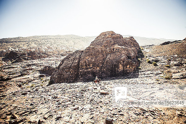 Ein Mann reitet auf einem Esel durch die Wüste bei Petra  Jordanien