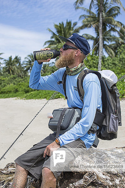 Angler Jonathan Jones drinks from a water bottle while hiking the beaches of Samoa in search of fly fishing waters.