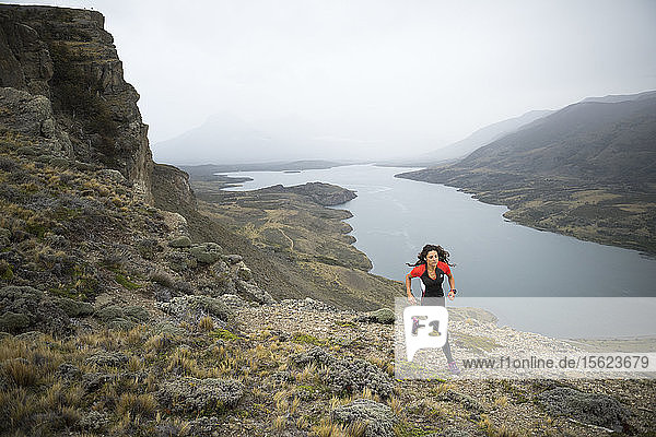 Front view shot of woman trail running in natural setting in Torres del Paine National Park  Magallanes region  Chile