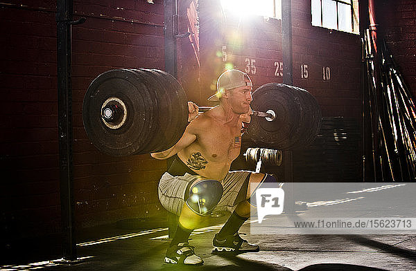 An athlete performs a squat at a crossfit gym in San Diego  CA.