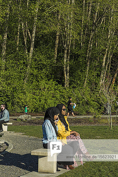 Zwei Frauen mit Hidschabs sitzen auf einer Bank im Park  Seattle  Washington  USA