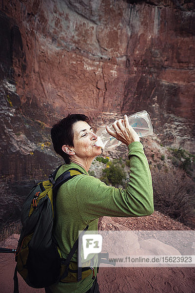 Blick von oben auf eine Wanderin  die auf dem South Kaibab Trail im Grand Canyon National Park anhält und aus ihrer Wasserflasche trinkt.