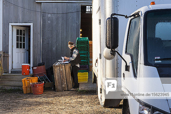 Ein Landwirt prüft noch einmal seine Auftragsliste  bevor er in seinen Lkw steigt  um die Ware auszuliefern.