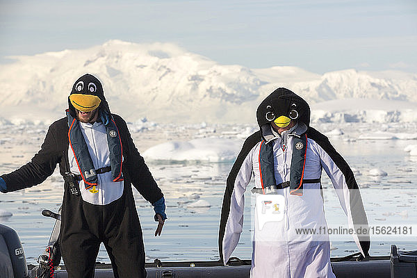 Als Pinguine verkleidete Besatzungsmitglieder einer Expeditionskreuzfahrt in die Antarktis in einer Zodiak in der Fournier Bay in der Gerlache Strait auf der antarktischen Halbinsel. Die antarktische Halbinsel ist eines der sich am schnellsten erwärmenden Gebiete der Erde.