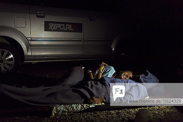 Schlafendes Paar in der Nähe des Autos bei Nacht  Batukaras  Java  Indonesien