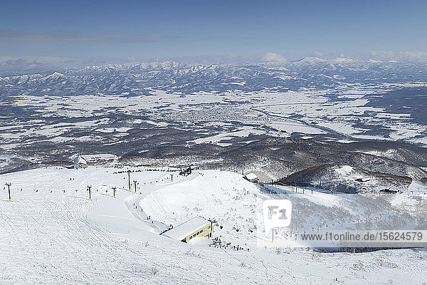 View from the summit of mount Annupuri  over the ski resort Niseko United on the Japanese island of Hokkaido. Niseko United is comprised of four resorts on the one mountain  Annupuri (1 308m). 100km south of Sapporo  Niseko Annupuri is a part of the Niseko-Shakotan-Otaru Kaigan Quasi-National Park and is the most eastern park of the Niseko Volcanic Group. Hokkaido  the north island of Japan  is geographically ideally located in the path of consistent weather systems that bring the cold air across the Sea of Japan from Siberia. This results in many of the resorts being absolutely dumped with powder that is renowned for being incredibly dry. Some of the Hokkaido ski resorts receive an amazing average of 14-18 meters of snowfall annually. Niseko is the powder capital of the world and as such is the most popular international ski destination in Japan. It offers an unforgettable experience for all levels of skier and snowboarder.