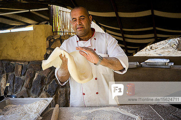 Der Koch wirft den Brotteig aus ï¾ shrakï¾ (Markook)ï¾  um ihn vor dem Garen auf der heißen sajï¾ (gewölbte Eisenplatte) sehr dünn zu machen  Dorf Wadi Rum  Gouvernement Aqaba  Jordanien