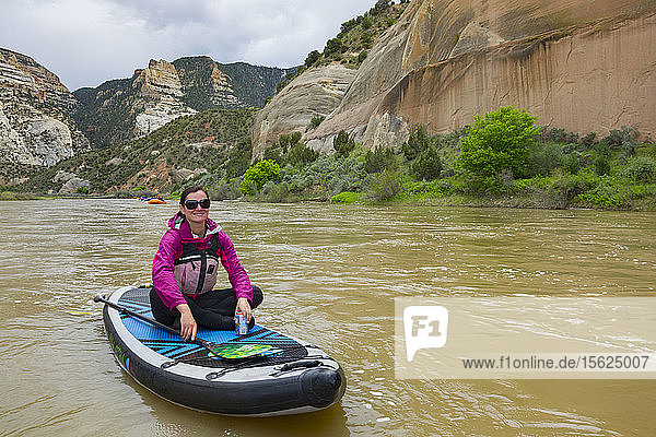 Lächelnde Frau sitzt auf Standup Paddleboard in Green River  Dinosaur National Monument  Utah  Usa