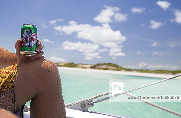 Ein männlicher Tourist trinkt während seines Urlaubs in Kuba auf einem Boot Cristal-Bier.