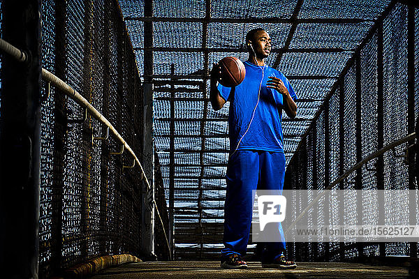 Ein sportlicher Mann steht auf einer Fußgängerbrücke in San Diego  CA  und spielt mit einem Basketball.