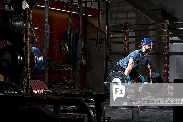 Ein athletischer Mann trainiert in einem düsteren Fitnessstudio in San Diego  Kalifornien  mit schweren Gewichten an einer Langhantel.