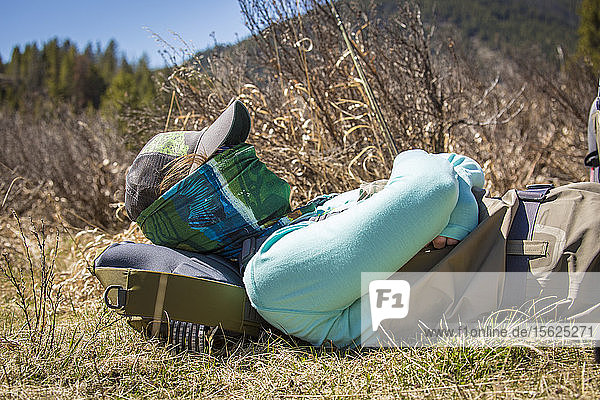 Young woman naps beside the Gallatin River in Montana.