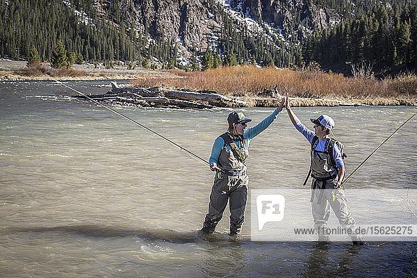 Zwei Frauen geben sich beim Angeln am Madison River in Montana die Hand.