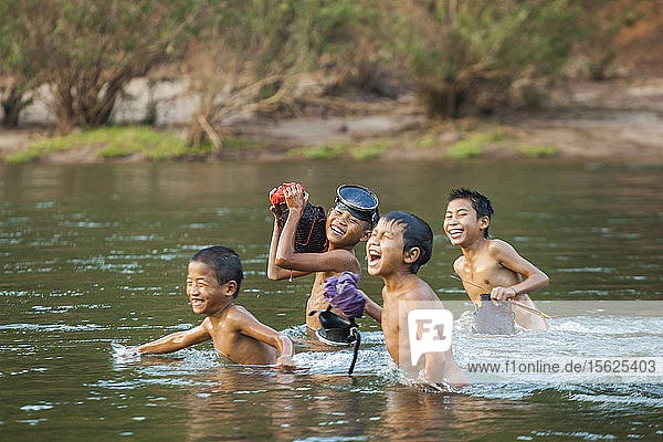 Naked young boys emerge from the water returning from spear fishing in the Nam Ou River outside Muang Hat Hin  Laos.