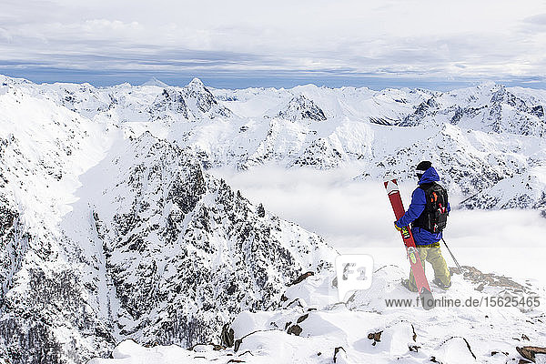 Ein Skifahrer steht auf einem felsigen Ausläufer und erkundet die Anden vom Cerro Catedral in Argentinien