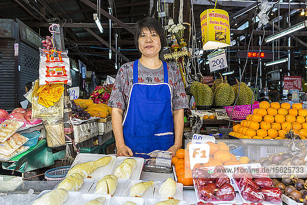Porträt eines Obstverkäufers mit Blick in die Kamera auf einem thailändischen Markt  Thailand