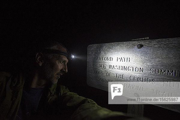 Person beim Lesen der Informationstafel mit Hilfe von Blitzlicht in Mount Washington