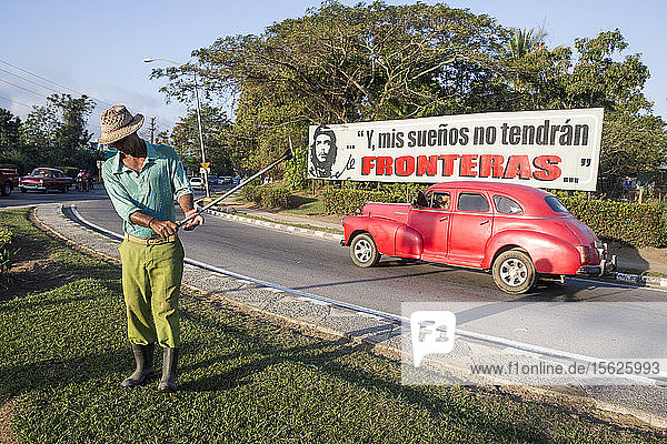 Full length shot of man cutting lawn on roadside Pinar del Rio Cuba