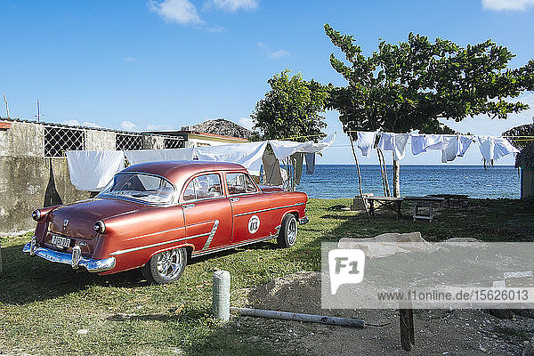 Ein roter Oldtimer parkt in der Nähe des Strandes in Playa Larga  Kuba