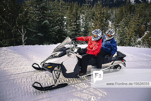 Side view shot of two adventurous men driving snowmobile  Callaghan Valley  Whistler  British Columbia  Canada