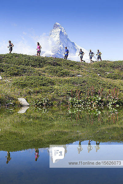 Trailrunner vor dem Matterhorn  das sich in einem Bergsee spiegelt. Diese Region der Schweizer Alpen ist ein beliebtes Ziel für Bergläufer  auch Skyrunner genannt.