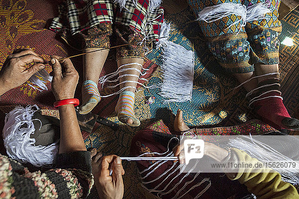 Frauen bereiten weiße Fadenarmbänder (Glücksbringer) bei einer Feier im Haus einer krebskranken Frau in Ban Huay Phouk  Laos  vor. Nach Aussage ihres Sohnes hatte die moderne westliche Medizin sie nicht heilen können  so dass es an der Zeit war  eine traditionellere Behandlung zu versuchen.