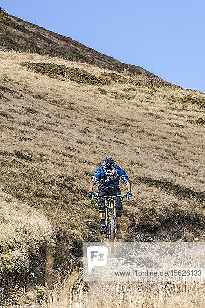 Landschaft mit einem Downhill-Biker  der am Ende des Tages im Chamonix-Tal  Chamonix  Hochsavoyen  Frankreich  auf einem Singletrail durch Gras fährt
