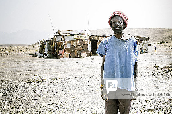 Ein Mann steht vor seinem Haus inmitten der Wüste in Namibia
