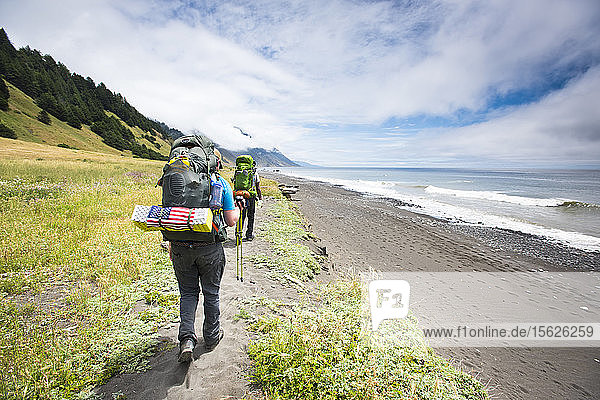 Two backpackers hiking on a trail near the ocean on the Lost Coast