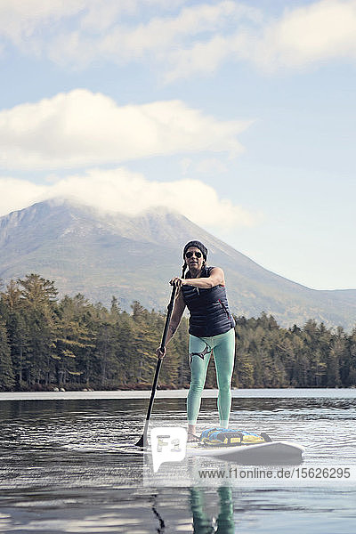 Eine junge Frau paddelt auf einem Teich in Maine.