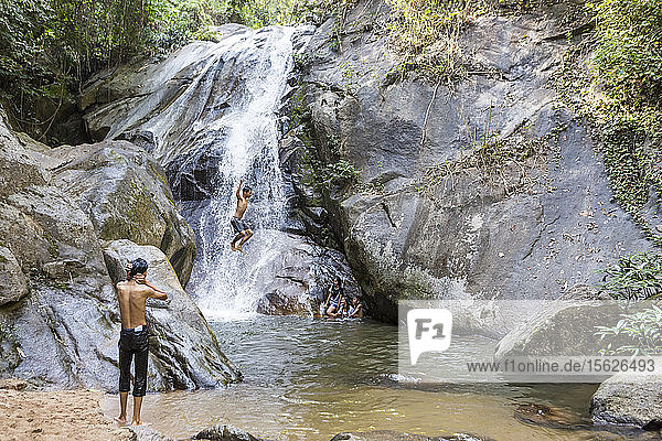 Shirtless boy jumping off rock at waterfall  Chiang Rai  Thailand