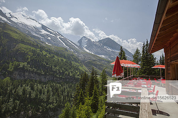Ein Lodge-Deck mit roten Sonnenschirmen bietet einen Blick auf die Schweizer Alpen. Kandersteg  Schweiz.