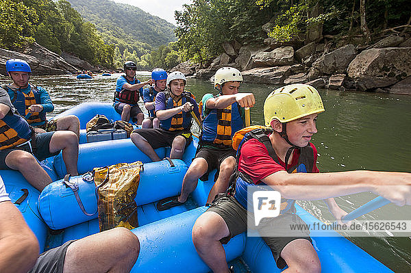 Order of the Arrow scouts paddle a raft through flat water heading towards another rapids on the New River  during a whitewater adventure in the New River Gorge  near Fayetteville  outside of the Summit Bechtel Reserve (SBR)  WV. The OA scouts are participating in a service and adventure program at SBR. Scouts on right  front to back - Walter Sterling  Noah Lopez  Patrick Bonorden  Nick Dannenmiller  and Raft guide. On left - Keith Roscoe