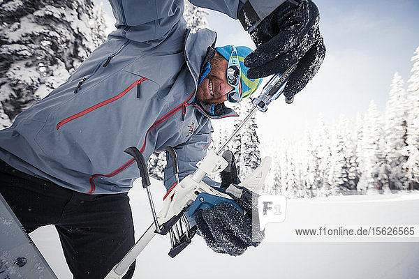Skifahrer mit Schraubenzieher zum Einstellen der Din-Einstellung an seiner Bindung