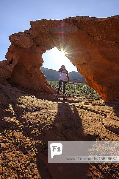 Foto mit einer Frau  die unter einem Felsbogen im Valley of Fire State Park  Nevada  USA  steht