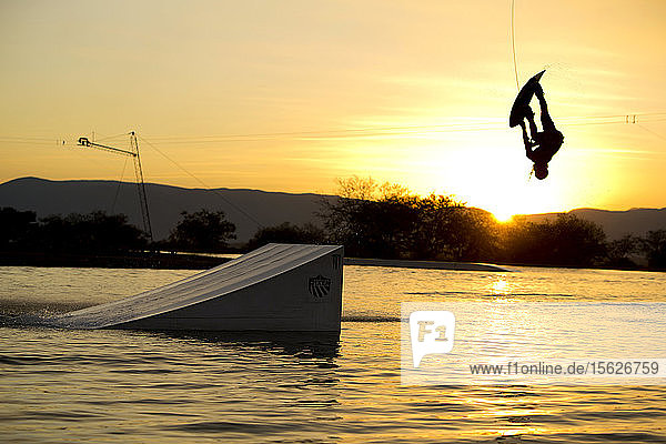 Silhouette of wakeboarder jumping from ramp against setting sun  Tequesquitengo  Morelos  Mexico