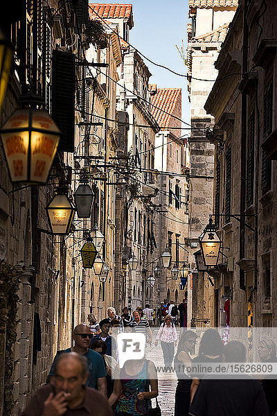 Menschen gehen durch eine enge Straße in Dubrovnik.