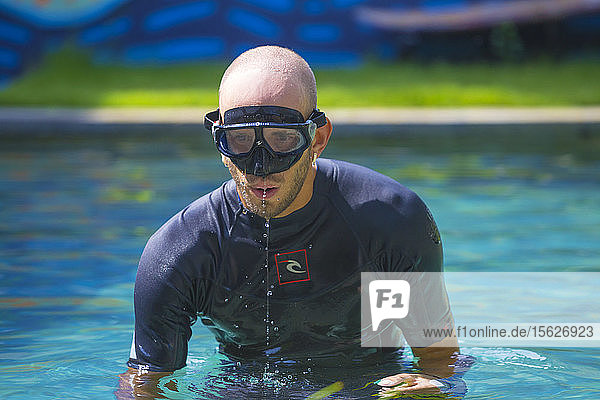 Porträt eines jungen Mannes mit Tauchmaske im Schwimmbad beim Freitauchtraining.