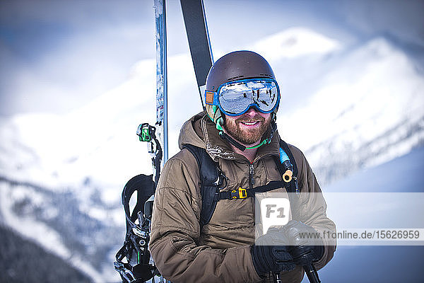 A skier smiles on a sunny day as he hikes across the top of Silverton Mountain in Colorado.