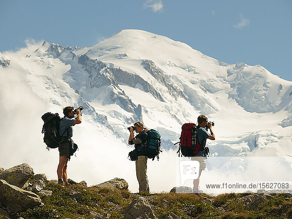 Drei Wanderer beim Fotografieren der französischen Alpen mit dem Mont Blanc im Hintergrund  Chamonix  Haute-Savoie  Frankreich