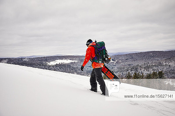 A backcountry snowboarder hiking a ridge in Vermont.